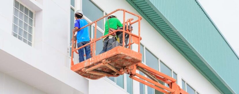 Worker man on a Scissor hydraulic Lift table Platform towards a factory roof at a construction site